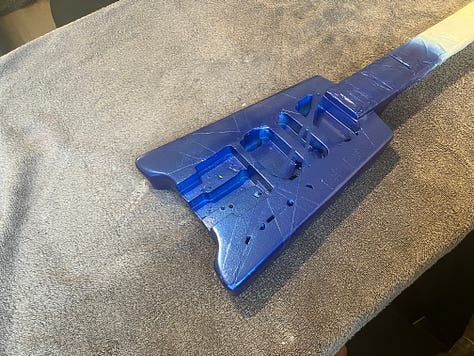 An image gallery showing a headless guitar being stripped down, sanded, repainted, and reassembled. By the end, it's blue with black and white stripes, and looks extremely shiny.